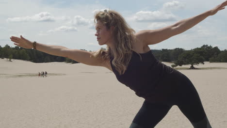 Beautiful-woman-doing-half-moon-pose-in-sand-dunes