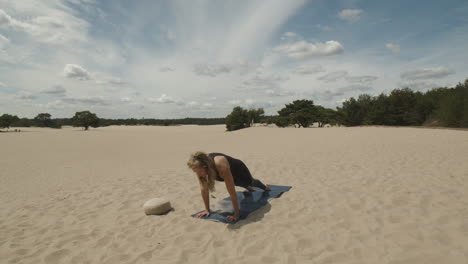 Woman-moving-into-yoga-child's-pose-in-sand-dunes