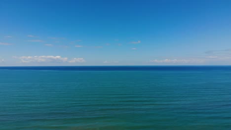 Blue-turquoise-sea-horizon-bordered-by-white-clouds-and-bright-sky,-beautiful-background-in-Mediterranean-coastline