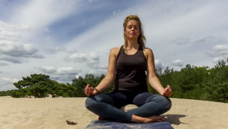 Time-lapse-of-Woman-meditating-in-sand-dunes---pan-left-right