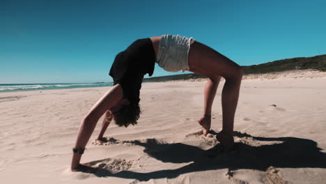 Slow-motion-zoom-out-shot-of-girl-doing-yoga-bridge-exercise-at-beach-during-sun