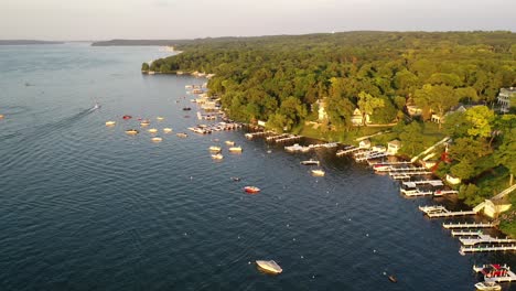 Beautiful-cottage-water-front-with-boats-docked-in-the-water-at-Lake-Geneva,-Wisconsin-filmed-from-a-aerial-view