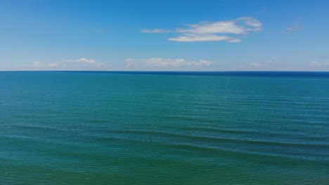 Blaue-Türkisfarbene-Meeresstruktur-Mit-Lebendigem,-Sauberem-Wasser-Unter-Hellem-Himmel-Mit-Weißen-Wolken