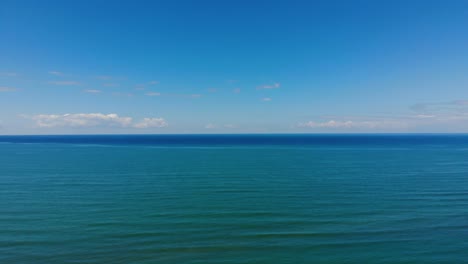 Sea-horizon-of-turquoise-blue-water-touching-bright-sky-and-white-clouds-on-a-summer-day