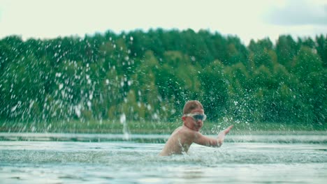 A-joyful-Caucasian-kid-splashes-the-water-with-hands-and-having-fun-in-the-lake