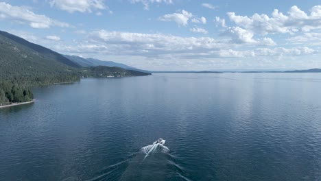 Lone-Motorboat-on-Picturesque-Calm-Lake-During-Summertime-on-Flathead-Lake-in-Kalispell,-Montana---Aerial-Drone-Tracking-View