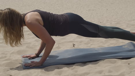 Beautiful-woman-doing-plank-and-upward-facing-dog-yoga-pose-in-sand-dunes