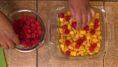 Making-a-peach-raspberry-crisp---overhead-view-of-hands-at-work
