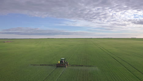 Aerial-cinematic-follow-shot-of-tractor-boom-spraying-fungicide-on-cereal-crop