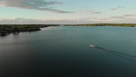Motorboat-Speeding-Across-The-Calm-Blue-Water-In-Black-Lake-In-New-York---aerial