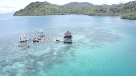 Schöne-Landschaft-Eines-Häuschens-Inmitten-Von-Kristallklarem-Blauem-Wasser-Am-Strand-In-Einem-Luxuriösen-Tropischen-Inselresort-Auf-Den-Philippinen---Reiseziel---Luftdrohnenaufnahme,-Umkreisende-Aufnahme