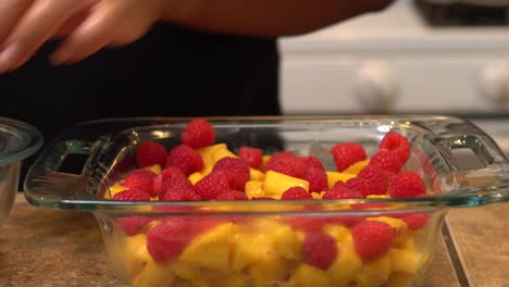 Adding-raspberries-to-a-homemade-crisp-recipe---isolated-front-view