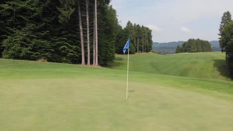 Blaue-Flagge-In-Einem-Golfloch-Auf-Einem-Wunderschönen-Golfplatz-Mitten-Im-Wald
