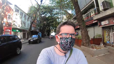 Männliche-Person-Mit-Brille-Und-Gesichtsmaske,-Die-Während-Des-Ausbruchs-Des-Covid-19-virus-Vom-Ipanema-strand-Durch-Die-Nachbarschaft-Zum-Stadtsee-In-Rio-De-Janeiro-Geht