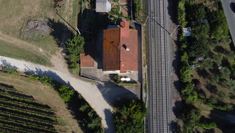Aerial-view-of-rural-Italian-house-next-to-railway-tracks-and-green-vineyards-Italian-countryside-,-Tuscany