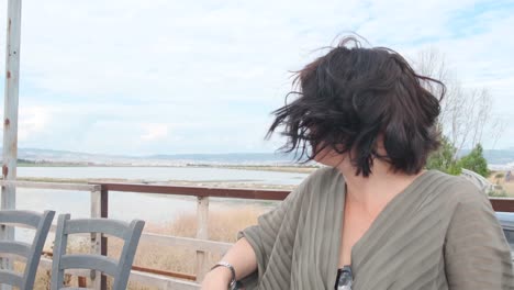 Closeup-Of-A-Woman-With-Hair-Blowing-on-the-Wind-While-Sitting-On-The-Wooden-Chair---Close-up-Shot