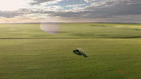 Dramatic-aerial-view-Tractor-spraying-crops-of-cereal-with-Fungicide,-Saskatchewan-Canada