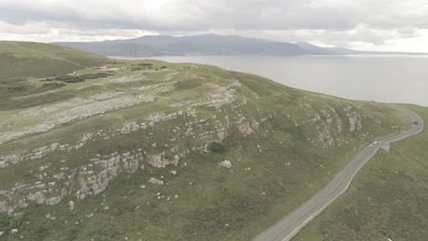 Sea-coastline-aerial-view-flying-above-Great-Orme-mountain-cliffs-Llandudno-Wales-orbit-left