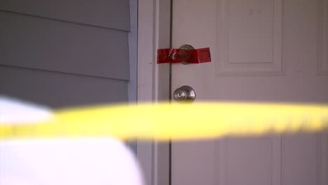 POLICE-CRIME-TAPE-IN-FOREGROUND-AND-POLICE-CRIME-TAPE-ON-DOOR