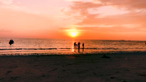 Silhouetten-Von-Menschen,-Die-Während-Der-Goldenen-Stunde-Des-Sonnenuntergangs-In-Koh-Tao,-Thailand,-Am-Strand-Von-Sairee-Stehen