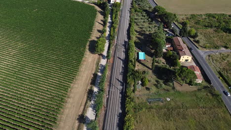 Sieci-town-highway,-railway-tracks-alongside-green-vineyards,-Tuscany,-Italy