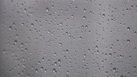 Close-up-of-small-raindrops-on-glass-window,-wet-surface-background,-static-shot