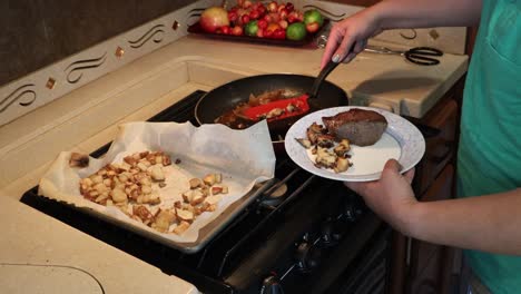 Woman-plating-steak,-grilled-onions,-sauteed-miatake-mushrooms-and-roasted-potatoes-in-a-tiny-home-kitchen