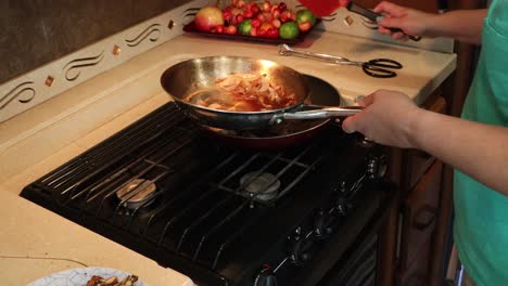 Woman-moving-cooked-steak-and-onions-to-a-different-frying-pan,-removes-roasted-potatoes-from-the-oven-and-plates-the-potatoes