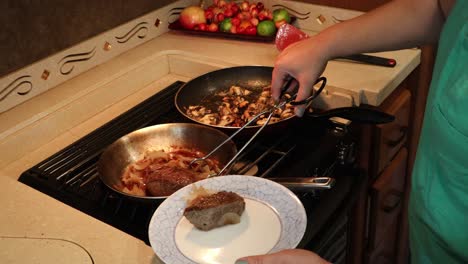Woman-plating-steak,-grilled-onions-and-sauteed-miatake-mushrooms-in-a-tiny-home-kitchen