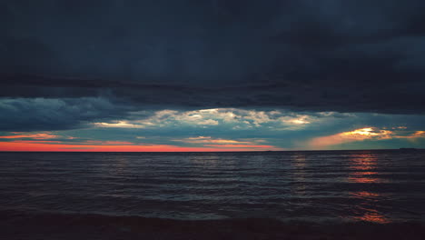 Beautiful-4K-UHD-Cinemagraph---seamless-video-loop-of-of-the-sunset-seen-from-a-romantic-beach-with-small-waves-at-the-Croatian-Mediterranean-seaside-with-dark-thunderstorm-clouds-mixed-with-red