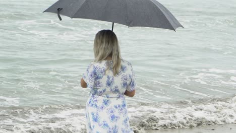 Frau,-Die-Am-Strand-Spazieren-Geht-Und-Mit-Regenschirm-Regnet