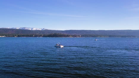 Recreational-boats-with-tourist-on-Big-Bear-Lake-on-sunny-day,-aerial-forward
