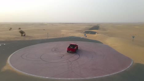 Red-truck-does-a-doughnut-in-the-middle-of-a-desert-road-roundabout-at-sunset-before-speeding-away-down-the-road