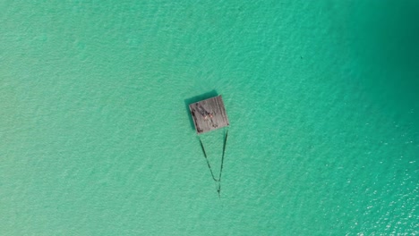 Remote-small-wooden-jetty-in-the-middle-of-exotic-lagoon-with-couple-standing-on-it-from-high-above