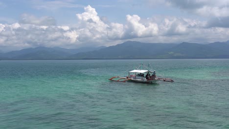 Barco-Con-Turistas-Navegando-En-El-Océano-Azul-Y-Llegando-Al-Resort-Dos-Palmas-Island-En-Puerto-Princesa,-Palawan,-Filipinas