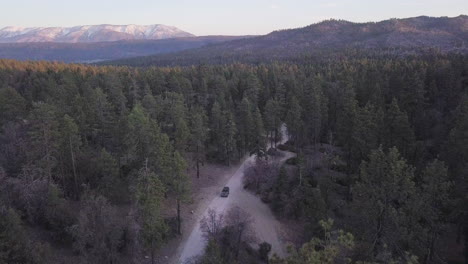 4WD-vehicle-on-dirt-track-country-road-to-remote-forest-campsite,-aerial-view