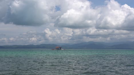 Boat-Sailing-On-The-Calm-Blue-Sea-On-A-Cloudy-day-From-The-Dos-Palmas-Island-Resort-And-Spa-In-Puerto-Princesa,-Palawan,-Philippines