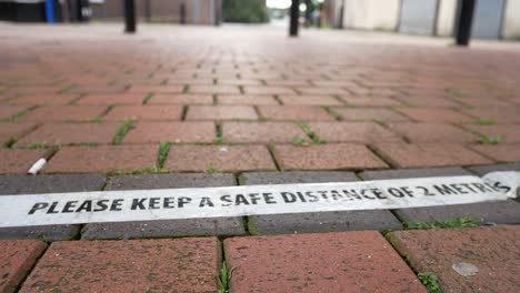 Corona-virus-safety-social-distancing-tape-on-town-brickwork-flooring