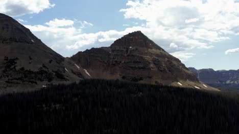 Atemberaubende-Luftdrohnenaufnahme-Eines-Großen,-Spitzen,-Felsigen-Berges-Mit-Schneekappen-Und-Des-Großen-Uintah-National-Forest-Darunter-An-Einem-Warmen-Sommertag-Im-Norden-Von-Utah
