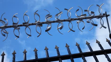 Prison-barbed-wire-steel-gate-looking-up-to-blue-cloudy-sky-slow-dolly-left