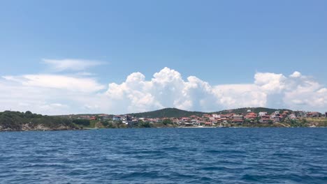 Approaching-majestic-island-of-Ammouliani-in-Sithonia-Greece-in-slow-motion-in-4k-and-scenic-cloudscape-with-cumulonimbus-cloud
