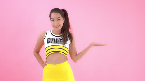 A-cheerleader-dressed-in-yellow-and-black-team-colors-gestures-with-her-hand-palm-up-to-the-copy-space-to-her-left