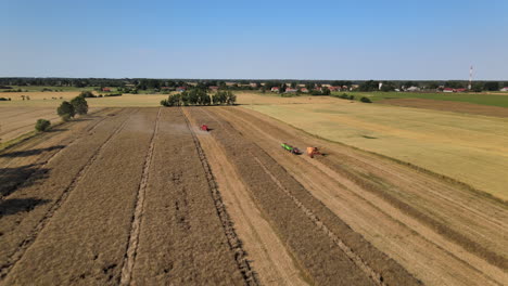 Dramatic-aerial-view-of-polish-farmlands-as-harvesters-work-continually-to-harvest-the-crops-of-barley