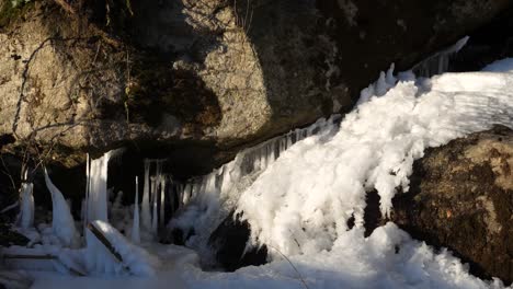 Unter-Einem-Großen-Felsen-Entspringt-Ein-Kleiner-Wasserfall-Aus-Einer-Eisschicht