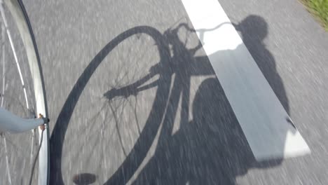 Shadow-of-cyclist-biking-on-asphalt-road,-60-fps