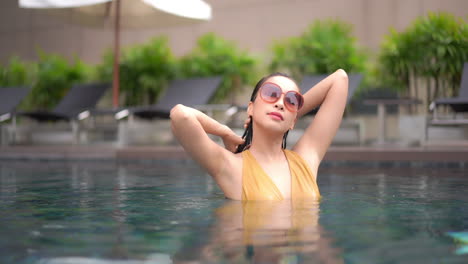 Classy-Attractive-Asian-Woman-Fixing-Her-Wet-Hair-in-Swimming-Pool,-Slow-Motion-Static-Shot