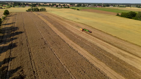 Aerial-view-showing-farm-machinery-working-on-agricultural-field-while-sun-is-shining