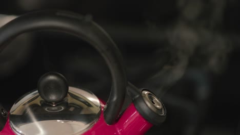 Close-up-of-a-red-tea-pot-bursting-with-steam-indicated-the-water-is-boiling