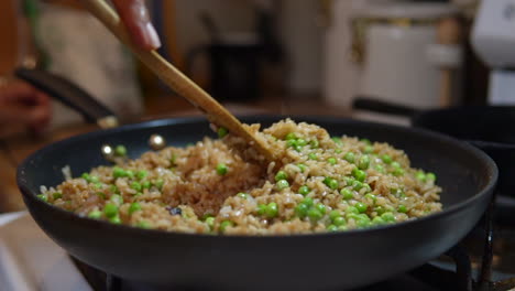 Stirring-fried-rice-and-peas-in-a-skillet,-pan-or-wok---slow-motion