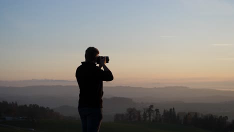 photographer-taking-picture-of-beautiful-dusky-landscape-behind-a-transmission-mast